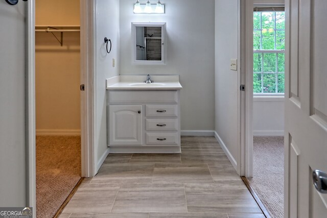 full bath with baseboards, a spacious closet, a wealth of natural light, and vanity