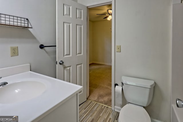 bathroom with vanity, toilet, a ceiling fan, baseboards, and wood finished floors