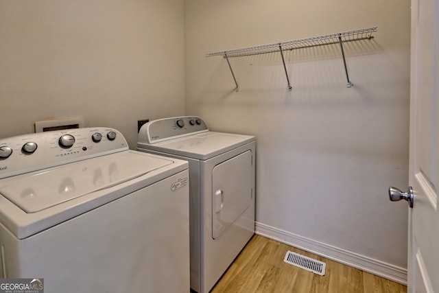 washroom with washing machine and clothes dryer, laundry area, baseboards, light wood-type flooring, and visible vents
