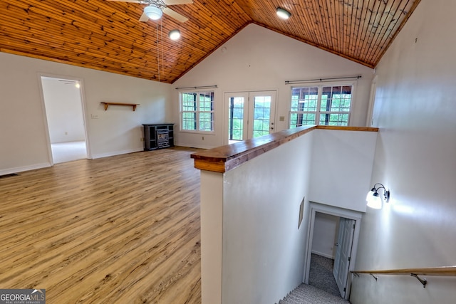 stairway featuring ceiling fan, a wood stove, high vaulted ceiling, baseboards, and wood finished floors