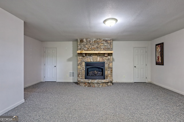 unfurnished living room featuring carpet flooring, a fireplace, a textured ceiling, baseboards, and visible vents