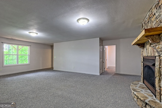 unfurnished living room featuring carpet floors, a textured ceiling, baseboards, and a stone fireplace