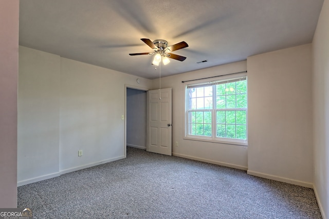carpeted spare room with baseboards, a ceiling fan, and visible vents