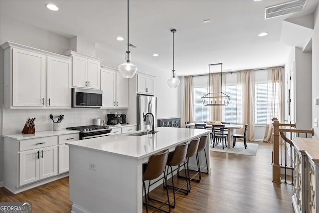 kitchen featuring tasteful backsplash, a sink, a breakfast bar, a center island with sink, and appliances with stainless steel finishes