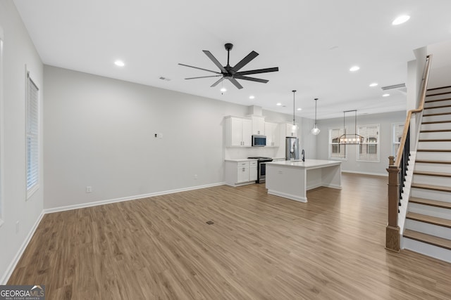 unfurnished living room with baseboards, recessed lighting, light wood-style floors, a ceiling fan, and stairs
