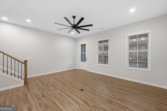 unfurnished living room featuring stairway, wood finished floors, ceiling fan, baseboards, and recessed lighting