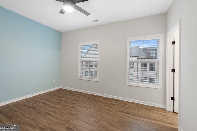 interior space with baseboards, plenty of natural light, a ceiling fan, and dark wood-style floors