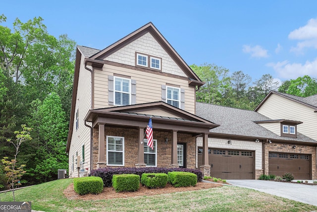 craftsman inspired home with a shingled roof, driveway, stone siding, and a front yard