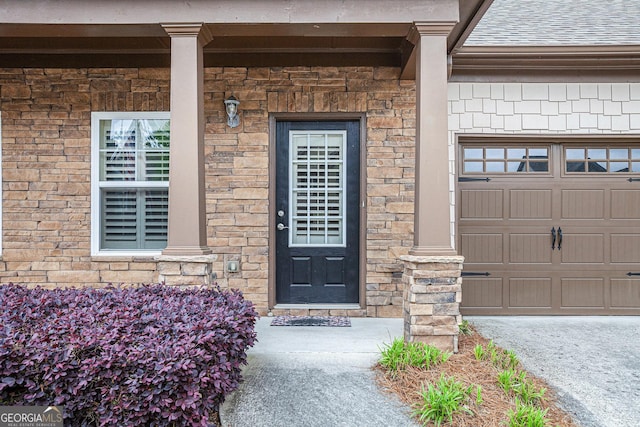 doorway to property with a shingled roof and an attached garage