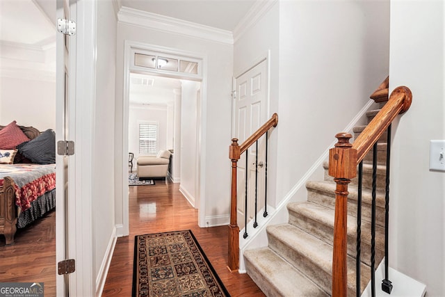 entryway with crown molding, dark wood finished floors, baseboards, visible vents, and stairway