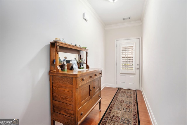 doorway to outside featuring crown molding, baseboards, visible vents, and light wood-style floors