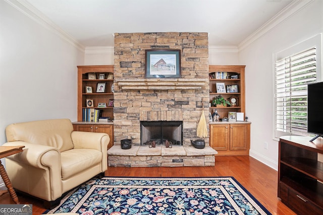 living area with baseboards, ornamental molding, wood finished floors, and a fireplace