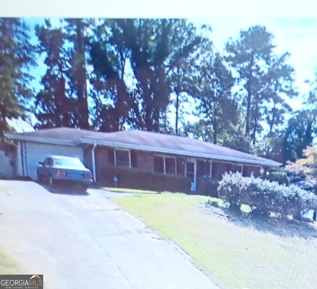 ranch-style home featuring driveway, a front yard, and a garage