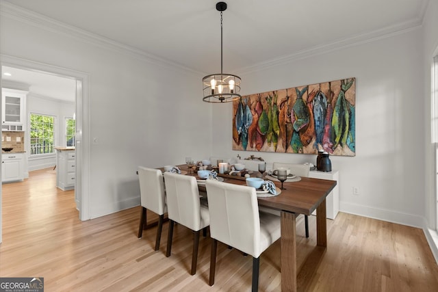 dining area featuring crown molding, a chandelier, light wood finished floors, and baseboards