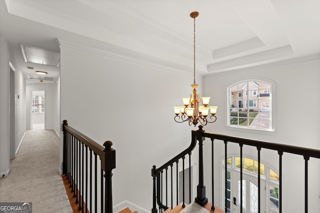 staircase with attic access, healthy amount of natural light, a chandelier, and carpet