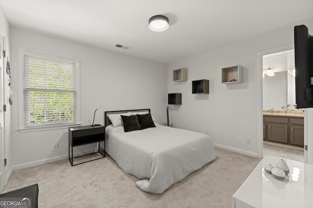 bedroom featuring light carpet, baseboards, and ensuite bath