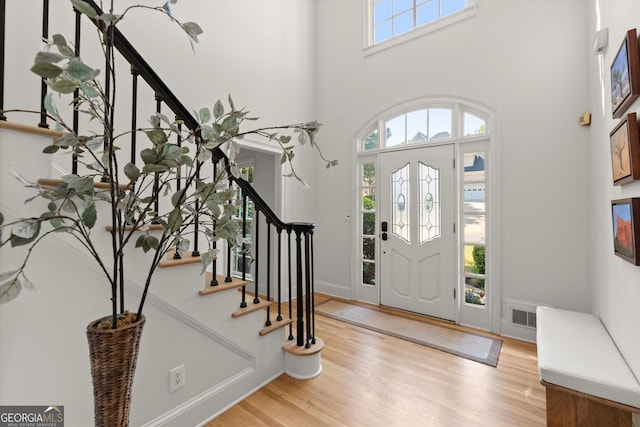 foyer entrance featuring stairway, wood finished floors, and a high ceiling
