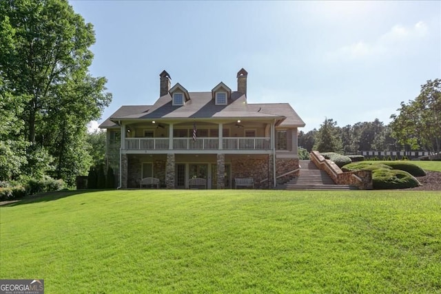 back of house featuring ceiling fan, a lawn, stone siding, and a chimney