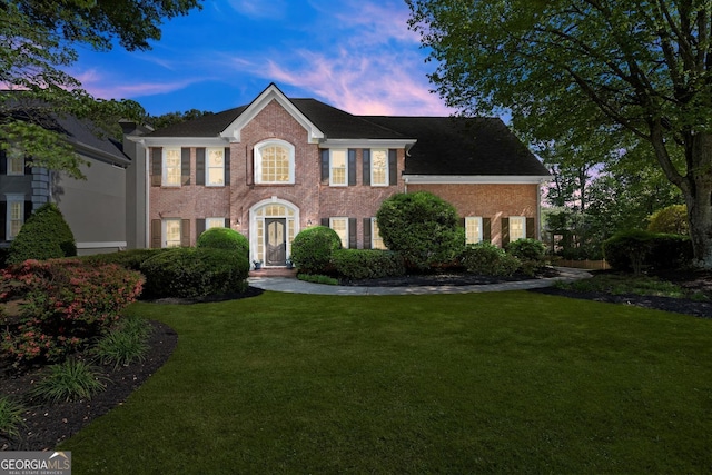 colonial-style house with a front lawn and brick siding