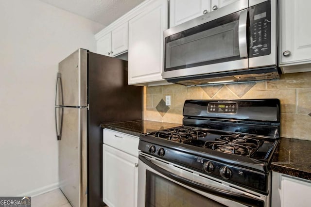 kitchen featuring dark stone counters, baseboards, backsplash, white cabinetry, and appliances with stainless steel finishes