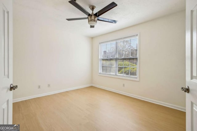 spare room featuring baseboards, wood finished floors, and ceiling fan