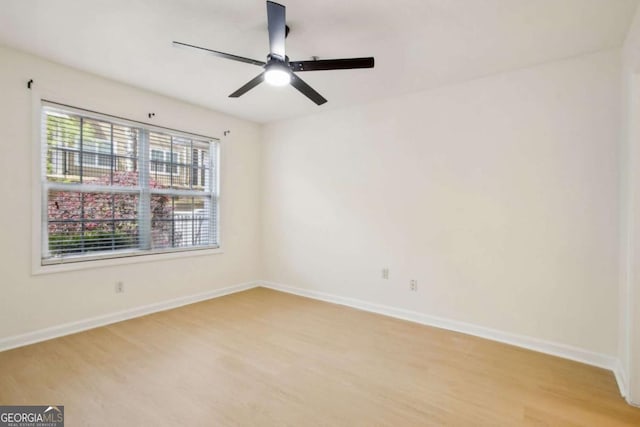 spare room featuring light wood-type flooring, baseboards, and ceiling fan