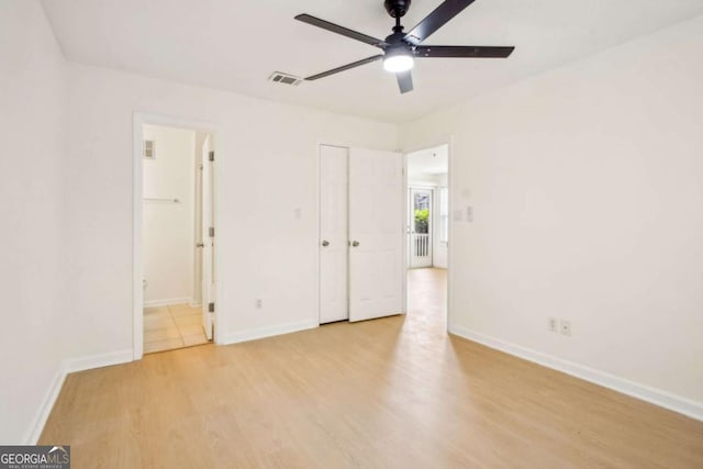 unfurnished bedroom featuring wood finished floors, visible vents, baseboards, and ensuite bathroom