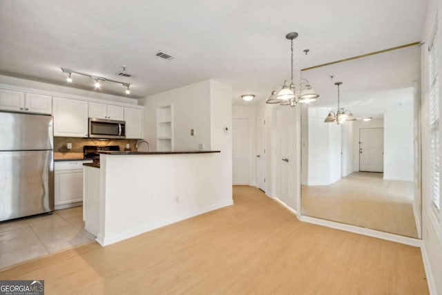 kitchen featuring dark countertops, tasteful backsplash, light wood finished floors, appliances with stainless steel finishes, and visible vents