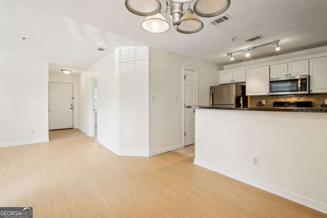 kitchen with dark countertops, visible vents, light wood finished floors, and stainless steel appliances