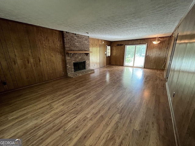 120 Treeside Dr NW, Rome, GA 30165 - unfurnished living room with a fireplace, wooden walls, wood finished floors, and a textured ceiling