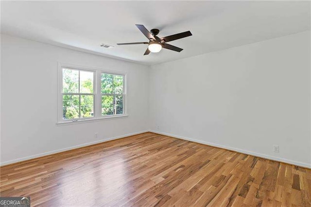 unfurnished room with a ceiling fan, visible vents, wood finished floors, and baseboards