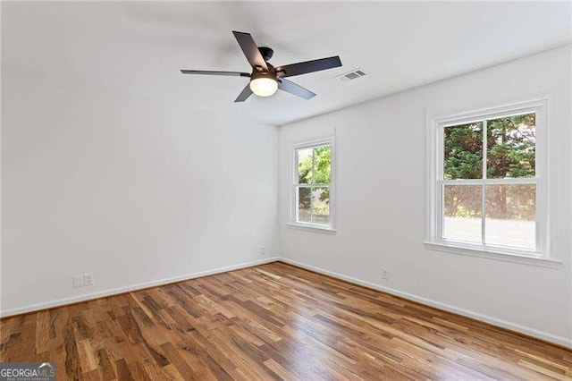 spare room with baseboards, visible vents, wood finished floors, and a healthy amount of sunlight