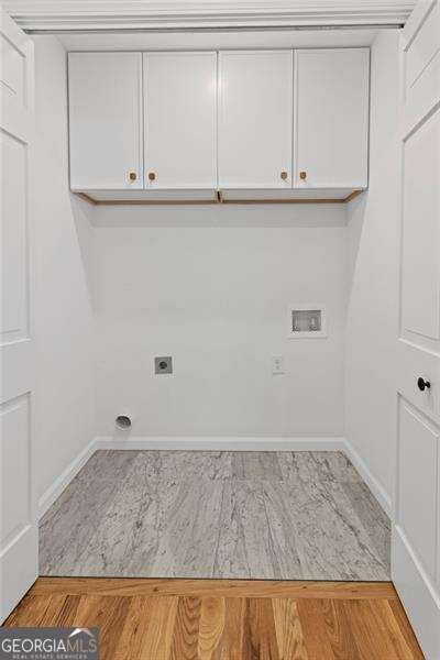 clothes washing area featuring hookup for an electric dryer, washer hookup, light wood-style floors, baseboards, and cabinet space