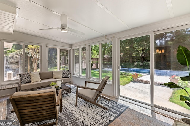 sunroom / solarium featuring a healthy amount of sunlight, brick floor, and vaulted ceiling
