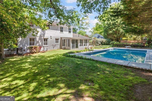 pool featuring a sunroom and a lawn