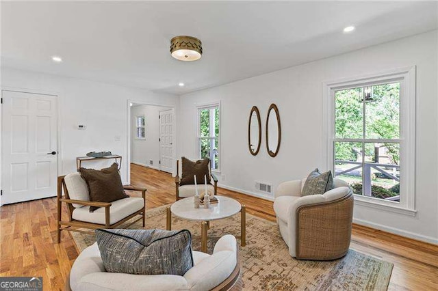 living area featuring baseboards, visible vents, light wood-style floors, and recessed lighting