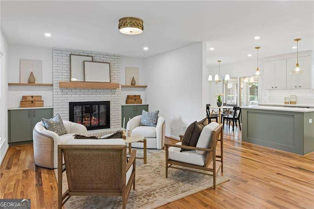 living area with a fireplace, recessed lighting, a chandelier, and light wood-type flooring