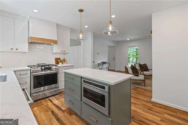 kitchen featuring premium range hood, light wood-type flooring, appliances with stainless steel finishes, and white cabinetry