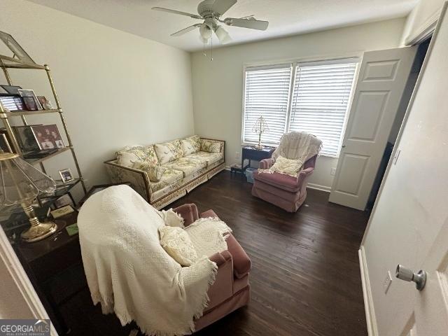 living area featuring baseboards, a ceiling fan, and wood finished floors