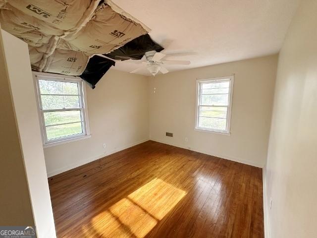 empty room featuring wood finished floors, a ceiling fan, and baseboards