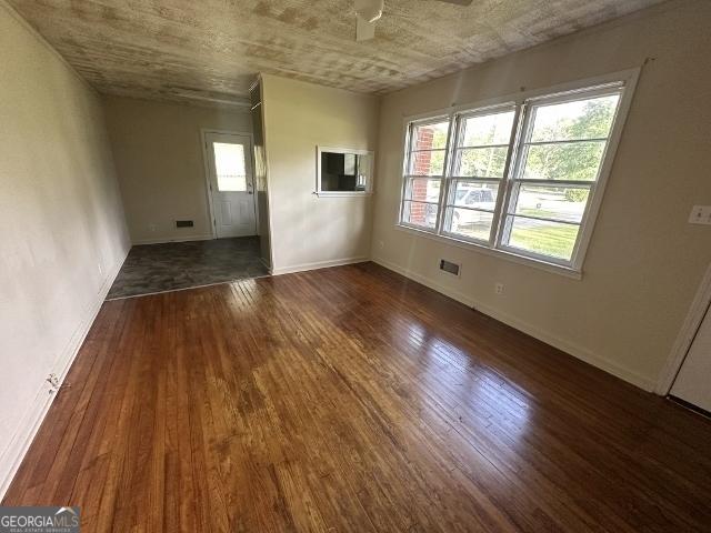 empty room with wood finished floors, baseboards, and ceiling fan