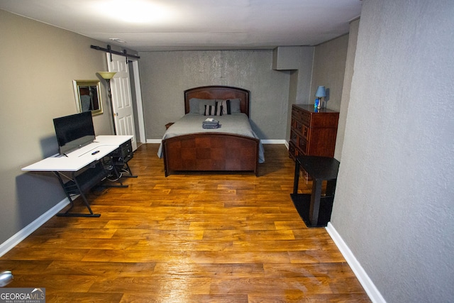 6147 Pritchett Dr, Powder Springs, GA 30127 - bedroom featuring a barn door, wood finished floors, a textured wall, and baseboards