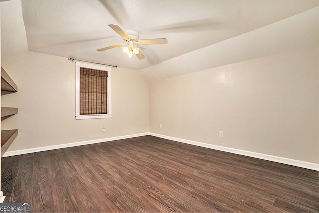 interior space featuring vaulted ceiling, baseboards, ceiling fan, and dark wood finished floors