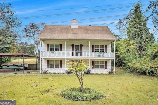 rear view of property featuring a yard, a shingled roof, a detached carport, and covered porch