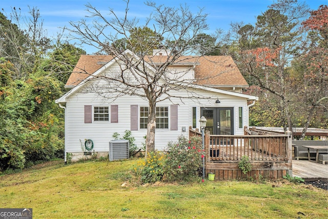 bungalow-style house with central AC unit, french doors, roof with shingles, a front yard, and a deck