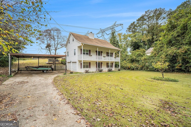 colonial inspired home featuring a chimney, concrete driveway, a carport, a porch, and a front yard