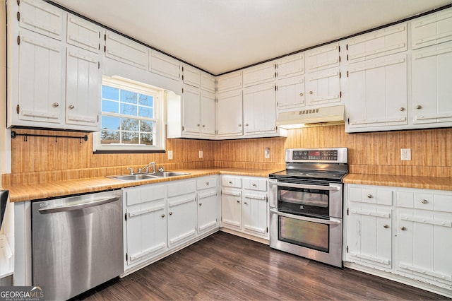 kitchen featuring under cabinet range hood, stainless steel appliances, white cabinetry, a sink, and dark wood-style flooring