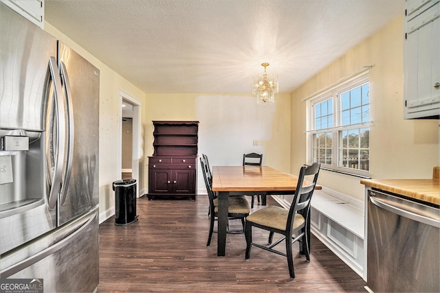 dining space featuring dark wood finished floors, a notable chandelier, and a textured ceiling