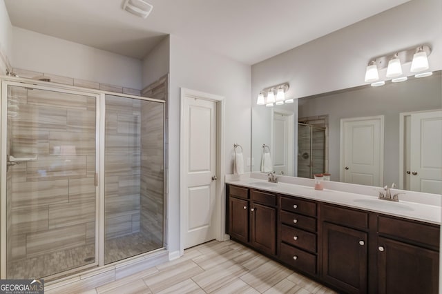bathroom with double vanity, a shower stall, visible vents, and a sink