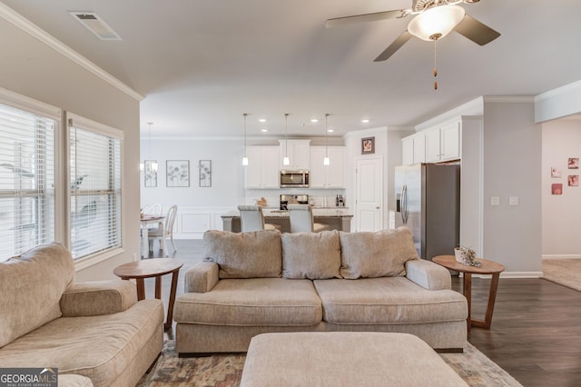 living room with dark wood-type flooring, visible vents, crown molding, and ceiling fan